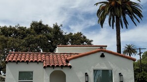 A small, single-story building with a white exterior, a red-tiled roof, and a palm tree in the background. - Central & NEW  3-bed 2 bath Spanish Bungalow in West Adams (Los Angeles)