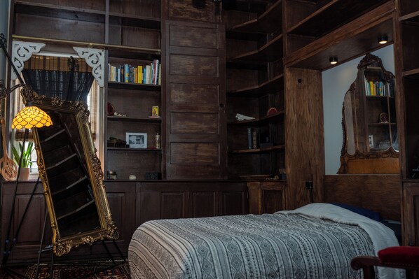 Une chambre à coucher avec un grand lit, des étagères en bois et un miroir doté d’un cadre orné.