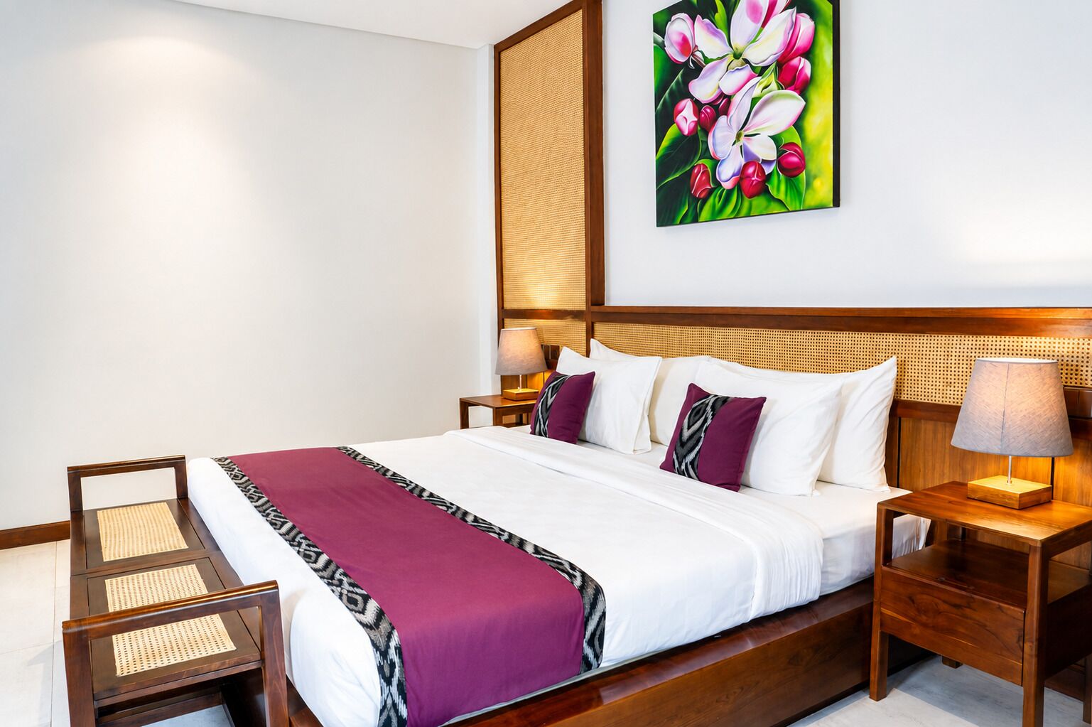 Habitación de hotel con una cama grande, cabecera de madera, mesita de noche con lámpara, una silla y un cuadro colgado en la pared.