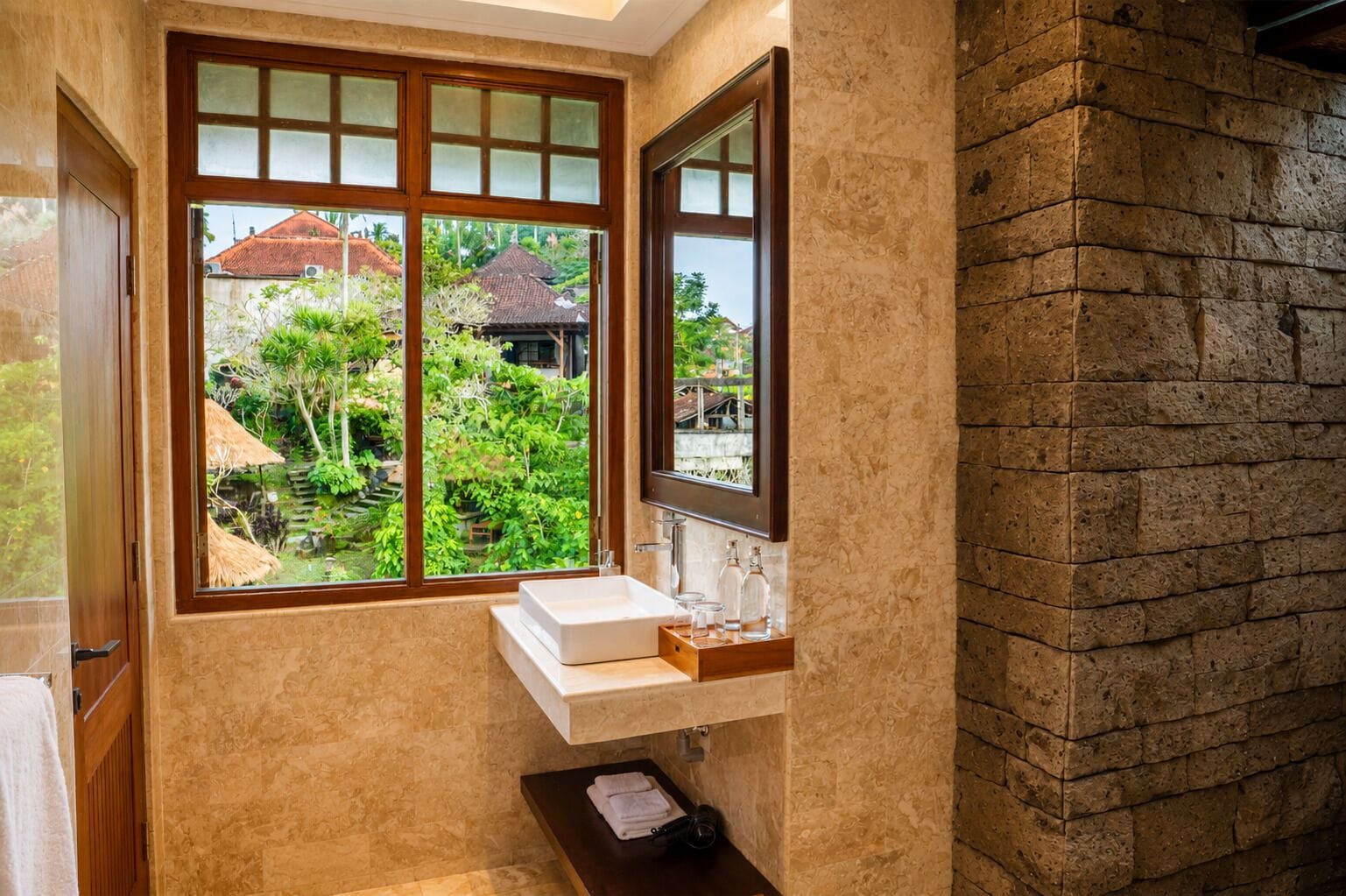 A bathroom with a large window, a white sink, and a mirror.