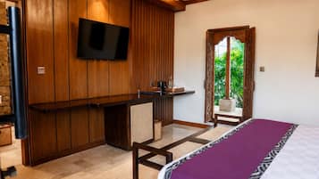 A room with a bed, a desk, a television, and a view of greenery outside.