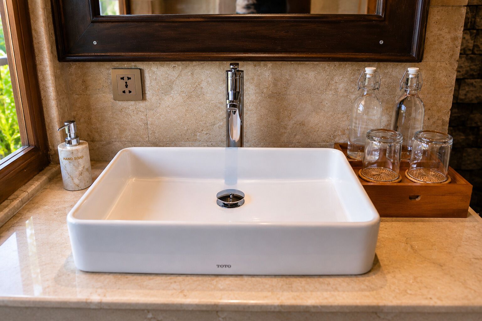 A white rectangular sink with a single faucet, a soap dispenser, and a wooden tray with glass bottles.