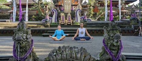Deux personnes méditent sur des tapis devant des sculptures en pierre richement décorées.