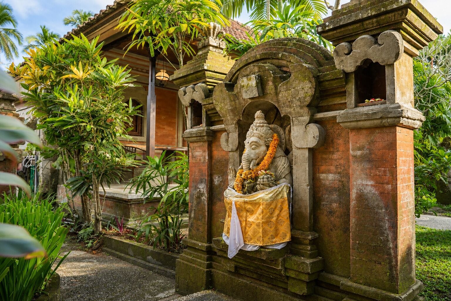 Un templo con una estatua de elefante, rodeado de exuberante vegetación.