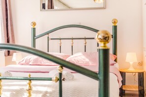 A bed with a green metal frame and gold accents, a bedside table with a lamp, and a mirror on the wall. - Charming Downtown Studio, Zagreb, Croatia (Zagreb)
