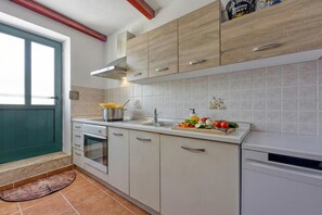 Une cuisine équipée d’une cuisinière, d’un four, d’un évier et de meubles de rangement en bois.