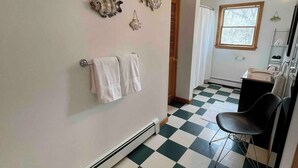 Une salle de bain avec un carrelage à motifs géométriques, un porte-serviettes avec des serviettes blanches et des œuvres d’art décoratives au mur.