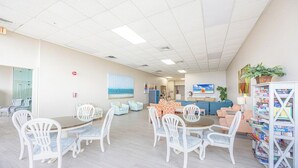 Un espace d’accueil avec un comptoir, un coin salon avec des chaises et des tables, une bibliothèque avec des magazines et un tableau accroché au mur.