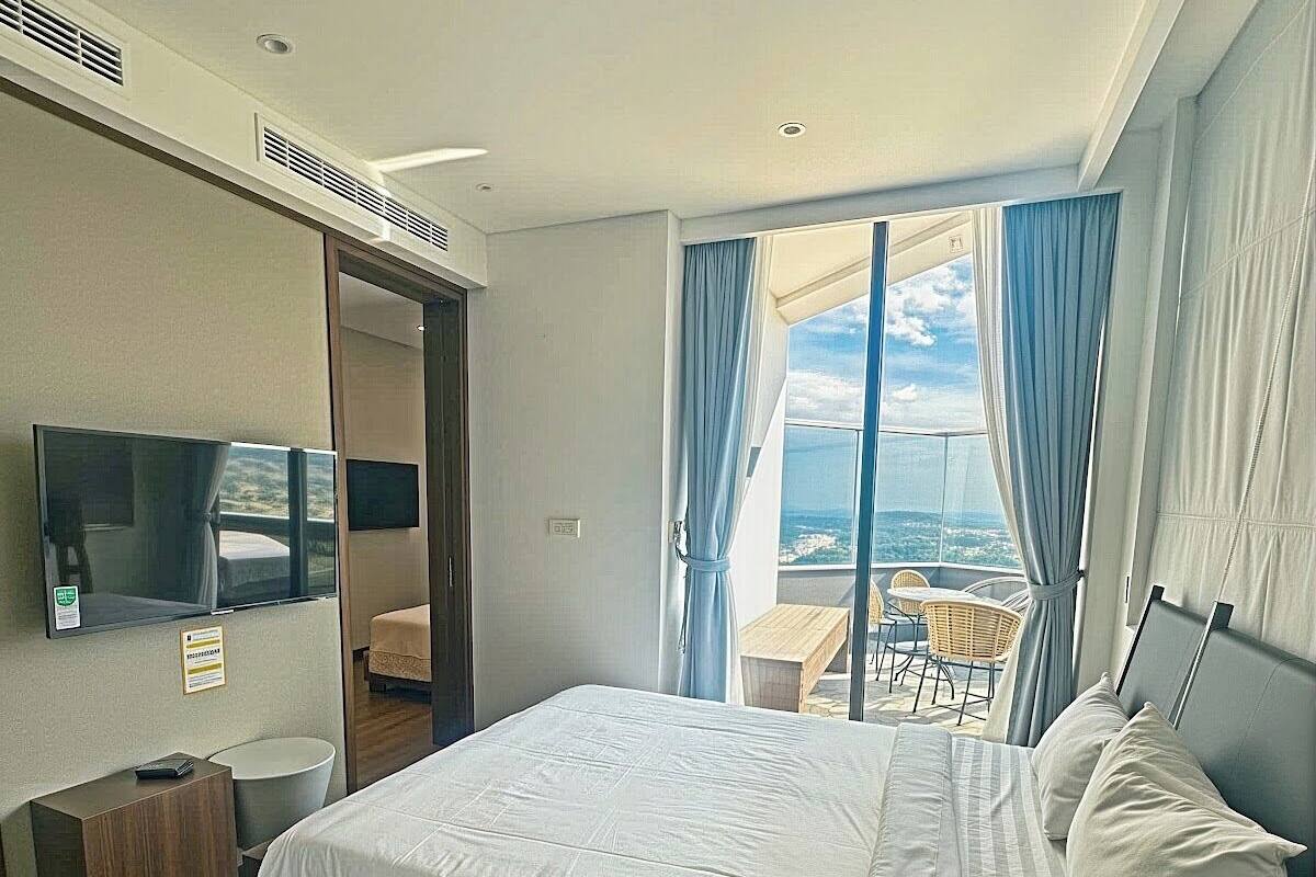 A hotel room with a bed, a TV, a desk, and a view of the outdoors.