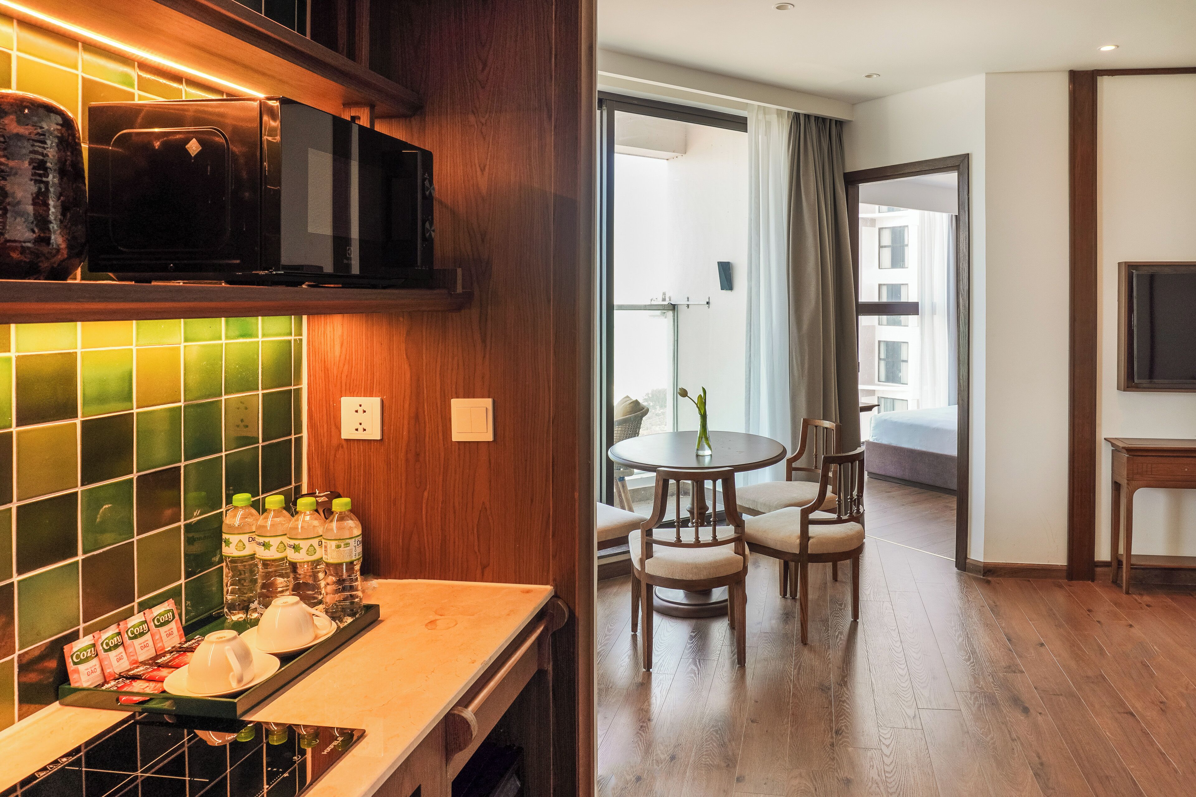 A kitchen with a microwave, a coffee station, and a dining area with a table and chairs.