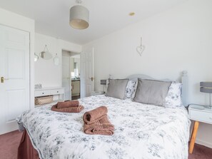 A bedroom with a bed, bedside tables, a mirror, and a hanging light fixture. - The Birches by Interhome (Liskeard)
