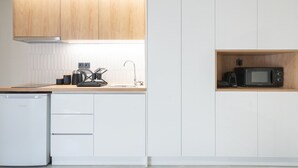 A modern kitchen with white cabinetry, a wooden countertop, a built-in microwave, and a compact dishwasher. - LIV - Comfortable Athens Apartment S8-1B (Athens)