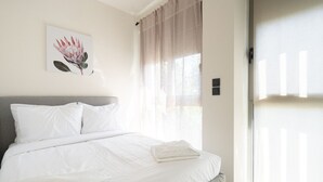 A neatly made bed with white linens, a grey headboard, and a single white pillow. - LIV - Comfortable Athens Apartment S8-1B (Athens)