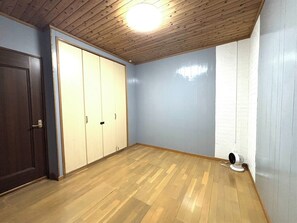 A room with wooden flooring, a ceiling fan, and a wardrobe.