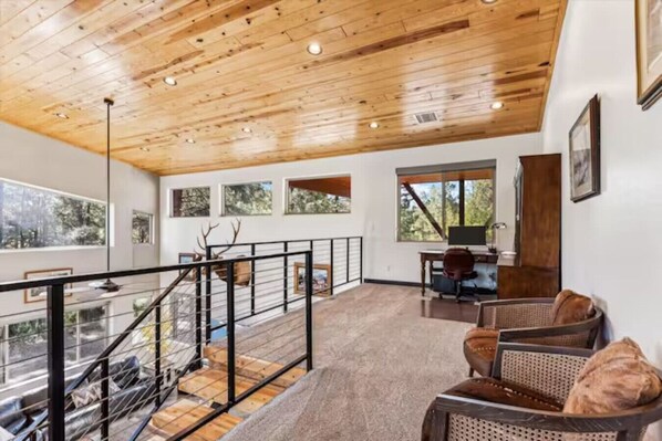 A spacious living area with a wooden ceiling, a staircase, and a view of the outdoors. - Richardson Rock Creek Ranch (Show Low)