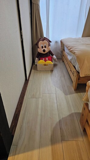 Ein Zimmer mit einem Bett, Holzboden und einem Stofftier in einem Korb.