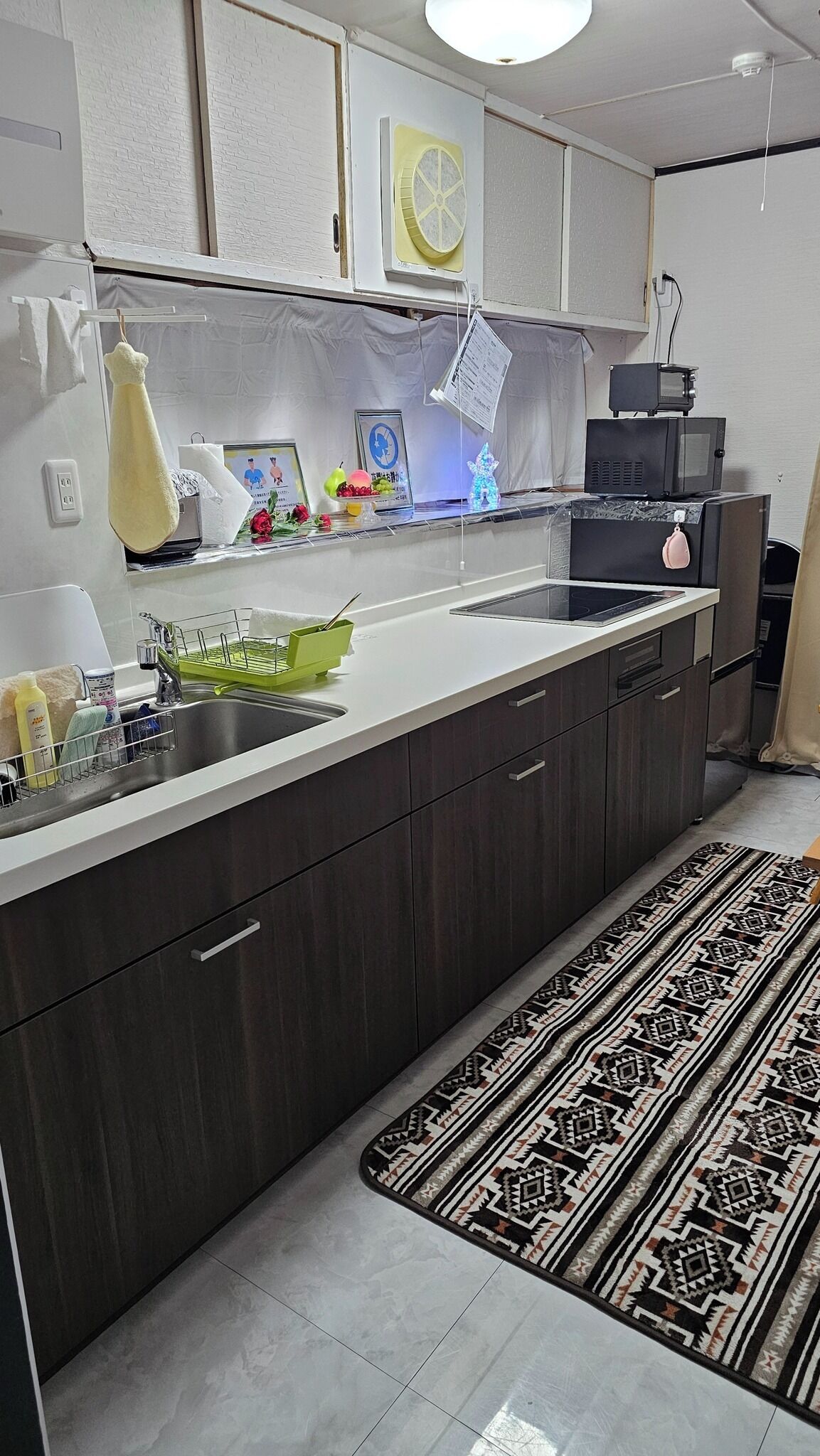 Een koelkast, een magnetron, een kookplaat, kookgerei, borden en bestek