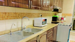 Una cocina con armarios de madera, lavadora, microondas y un lavabo.