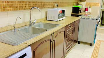 A kitchen with wooden cabinets, a washing machine, a microwave, and a sink.