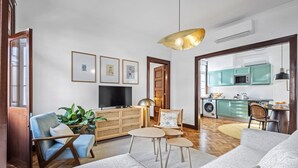 Een moderne woonkamer met een bank, salontafel, televisie en een eethoek.