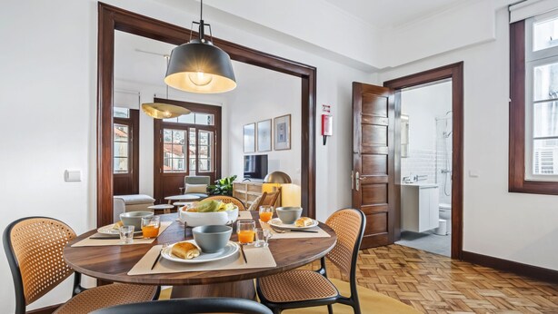 Een eethoek met een ronde tafel, rieten stoelen en een hanglamp.