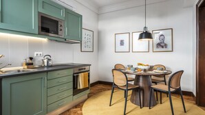 Een moderne keuken met blauwgroene kastjes, een ingebouwde oven, en een eetgedeelte met een ronde tafel en stoelen.