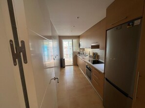 Eine moderne Küche mit einem Edelstahl-Kühlschrank, Holzschränken und einer Schiebetür, die auf eine Terrasse führt.