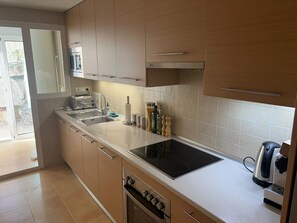 Eine moderne Küche mit Backofen, Kochfeld und Wasserkocher.