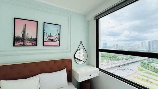 A bedroom with a bed, a bedside table, a mirror, and two framed pictures on the wall. - Vinhomes Sky Lake Luxury - Chup Housing  (Hanoi)