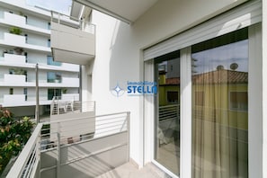 A modern apartment with balconies, a sliding glass door, and a logo for 'immobiliaria STELLA'.