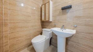 Een badkamer met toilet, wastafel en spiegel.