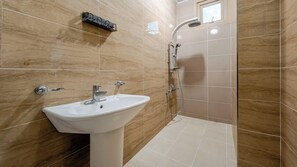 Een badkamer met wastafel, douche en betegelde wanden.