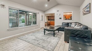 A spacious living room with a large window, a ceiling fan, and a view of the backyard. - “Spacious 4BR Home with Private Pool Perfect for Families!” (San Antonio)