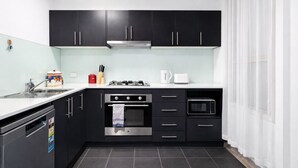 Une cuisine moderne avec des meubles noirs, une cuisinière en acier inoxydable, un four à micro-ondes et un lave-vaisselle.