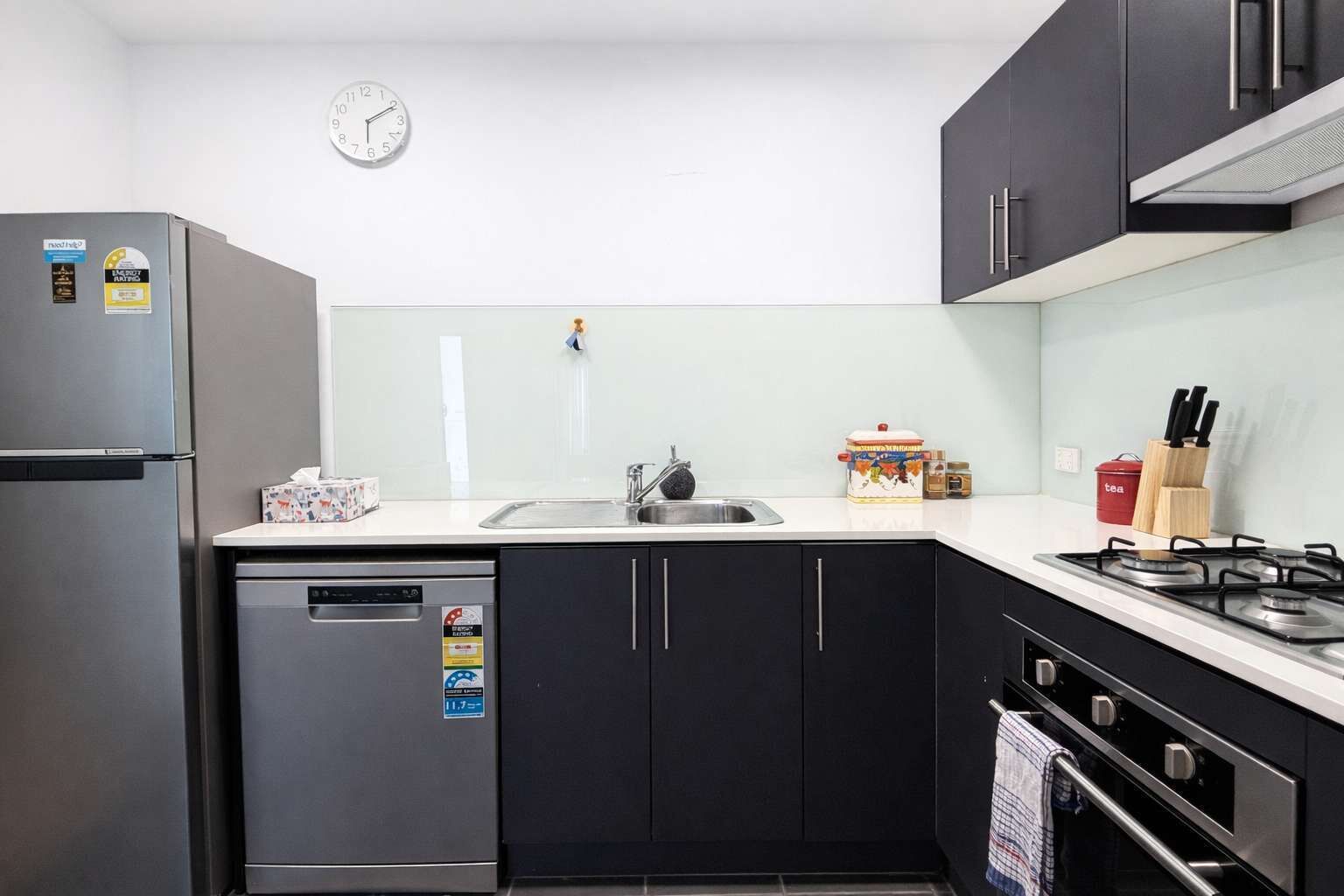 Een kleine keuken met een koelkast, vaatwasser, gootsteen en fornuis.