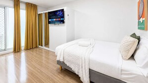 A modern hotel room with a bed, a TV, and a view of the outdoors. - Brunswick 1BR: City & Comfort w/ Free Parking (Brunswick)