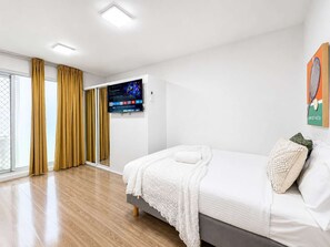 Una habitación de hotel moderna con una cama, un televisor y vistas al exterior.