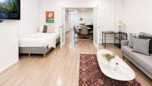 A modern hotel room with a bed, a sofa, a dining area, and a TV mounted on the wall. - Brunswick 1BR: City & Comfort w/ Free Parking (Brunswick)