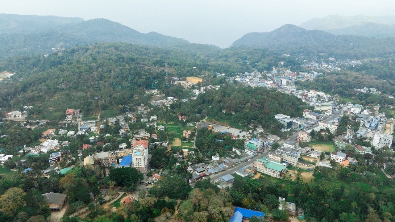 Vista aérea de uma cidade com edifícios, ruas e vegetação ao redor.