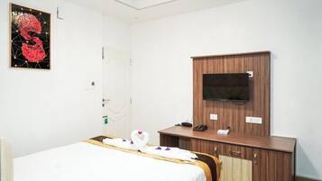 Una habitación de hotel con una cama, un armario de madera con televisión y una obra de arte en la pared.