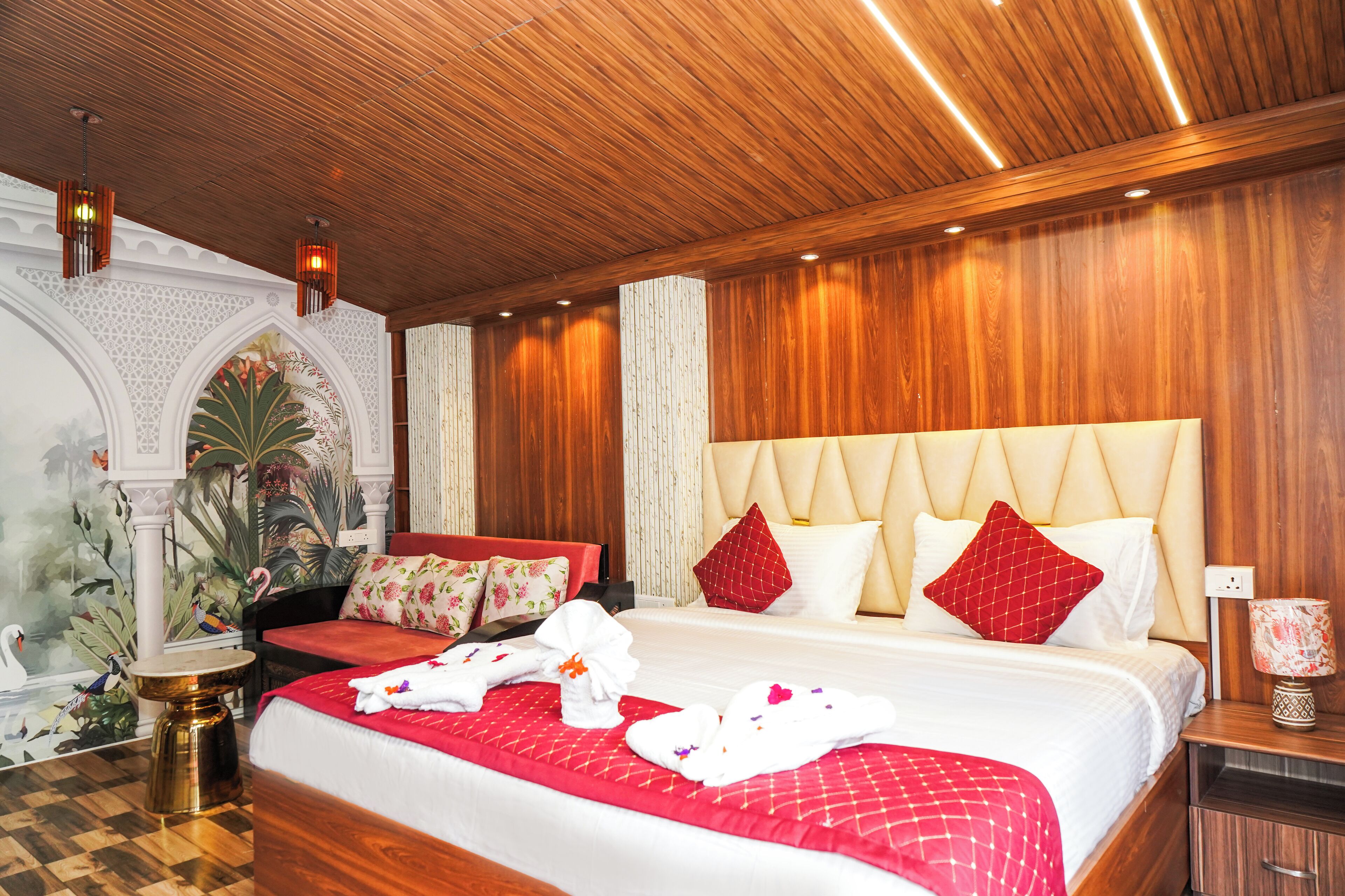 A hotel room with a large bed, wooden ceiling, and a decorative wall with a floral mural.