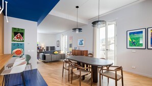 A modern living room with a dining area, a sofa, a TV, and artwork on the walls.