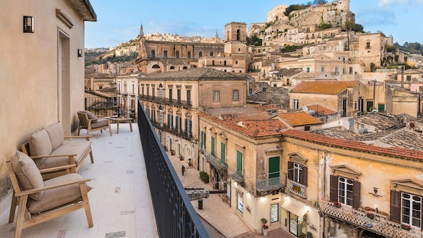 A balcony with a view of historic buildings and a castle on a hill.
