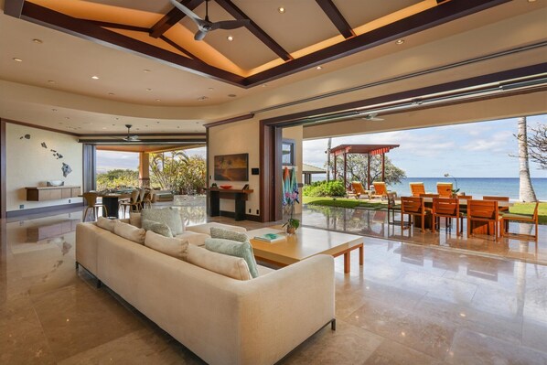 A spacious living area with a large sofa, a coffee table, and a view of the ocean.