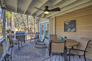 An outdoor patio with a grill, seating, and a ceiling fan.