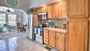 A kitchen with wooden cabinets, stainless steel appliances, and a tiled floor.