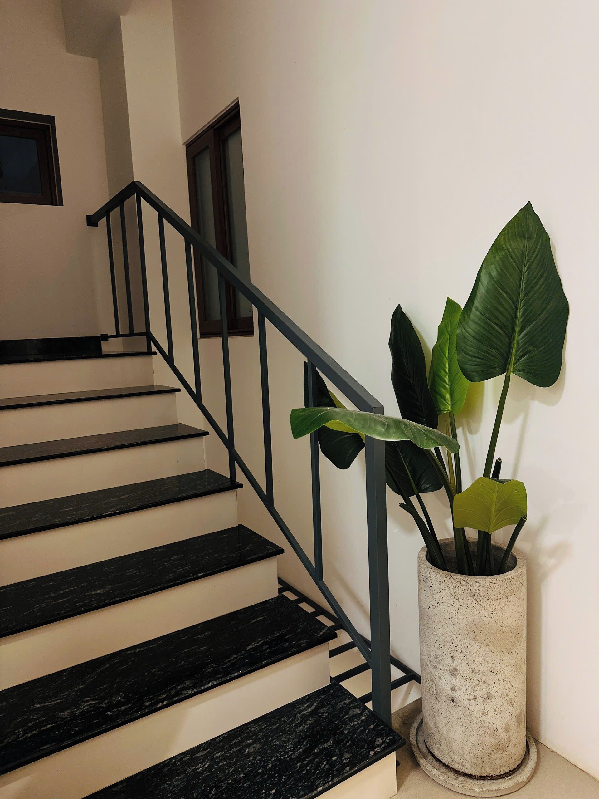 A staircase with black steps and a metal railing, leading to a landing.