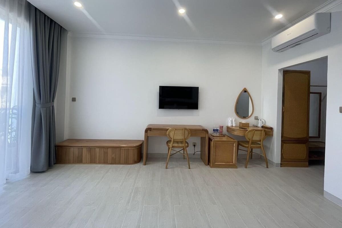 Una habitación moderna con un escritorio de madera, dos sillas, un televisor y un pequeño banco.