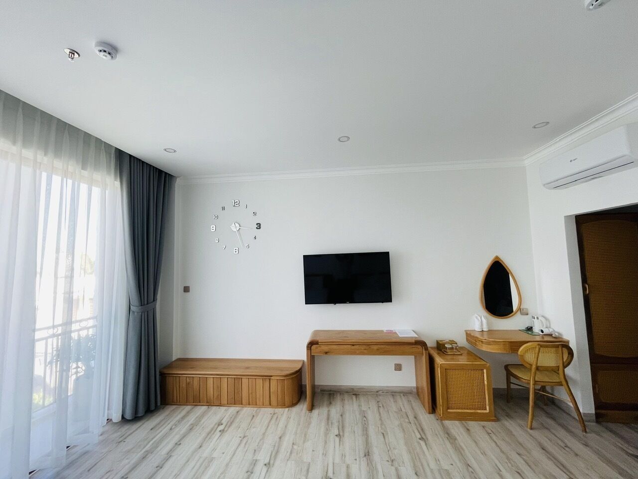 A hotel room with a bed, a desk, a chair, a television, and a window with curtains.