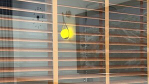 Une pièce avec des stores horizontaux, un interrupteur visible et un luminaire suspendu.